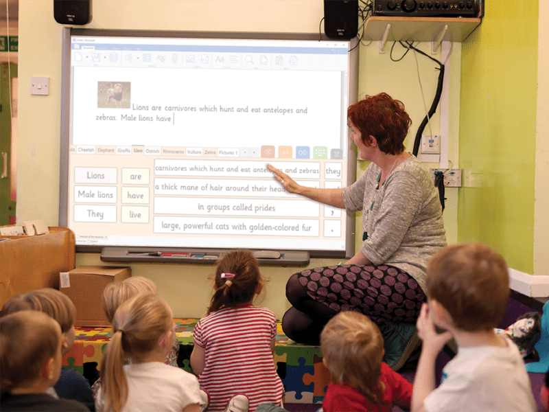 A teacher demonstrating digital literacy by using Clicker on an interactive whiteboard.